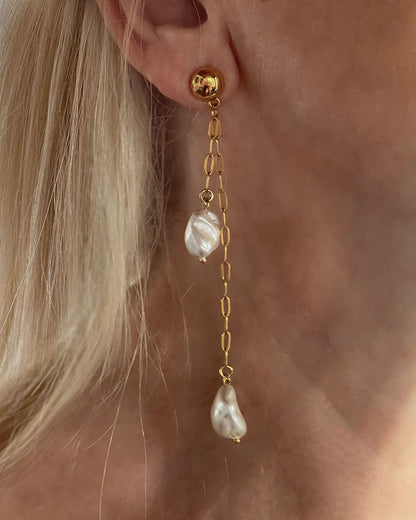 Model wearing the Long Drop Pearl Shell Earrings, a pair of stud earrings featuring two paperclip chains with shell pearl pendants.