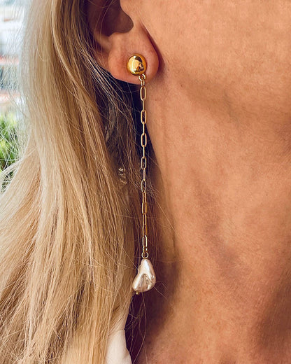 Model wearing the Long Pearl Shell Earrings, a pair of stud earrings featuring a paperclip chain with a shell pearl pendant.