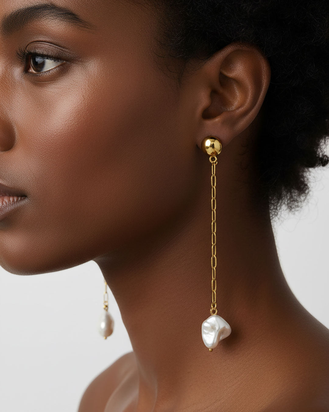 Model wearing the Long Pearl Shell Earrings, a pair of stud earrings featuring a paperclip chain with a shell pearl pendant.