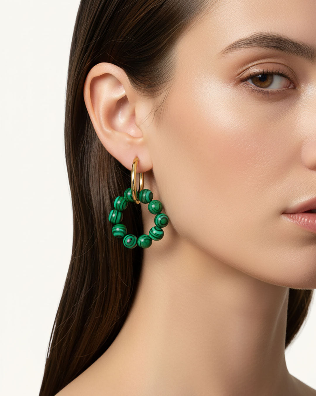 Model wearing gold hoop earrings with malachite green beads