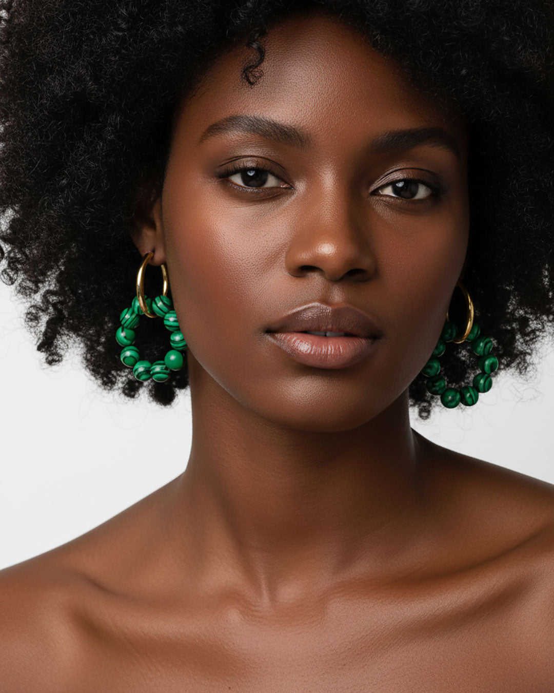 Model wearing gold hoop earrings with malachite green beads