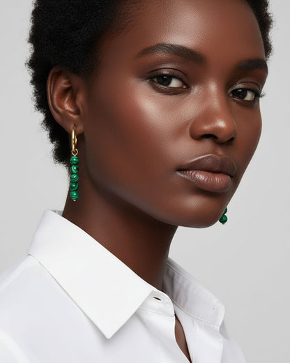 Model wearing gold hoop earrings with malachite green beads