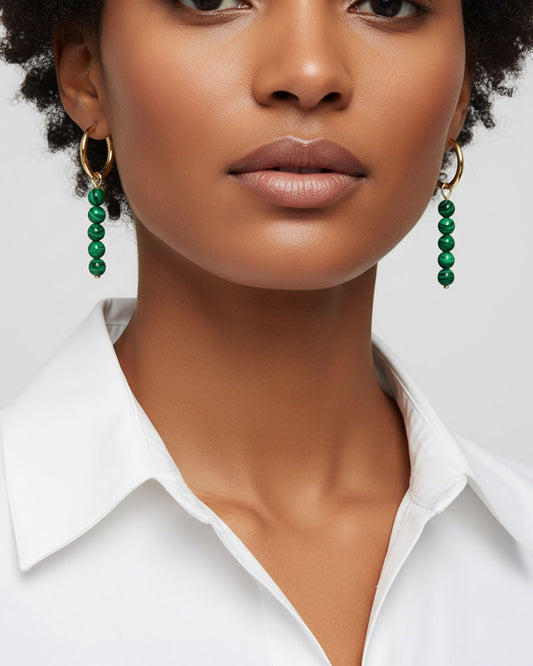 Model wearing gold hoop earrings with malachite green beads