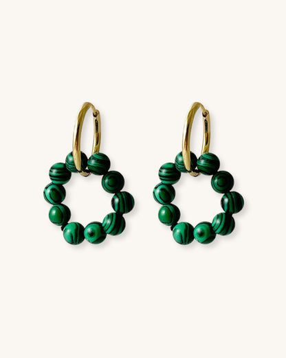 Pair of gold hoop earrings with rounded style malachite beads on a white background