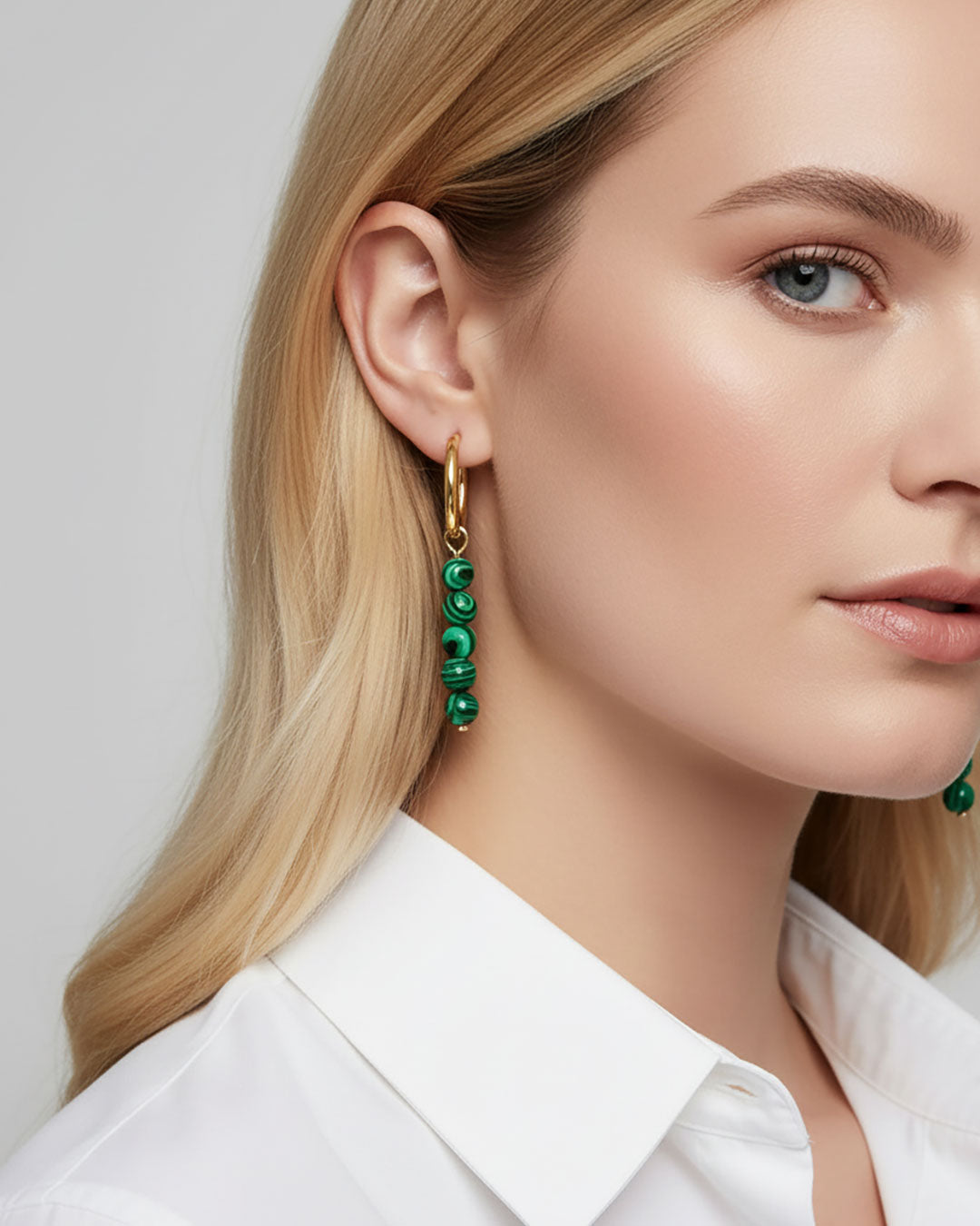 Model wearing gold hoop earrings with malachite green beads