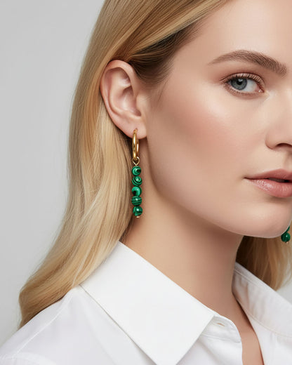 Model wearing gold hoop earrings with malachite green beads