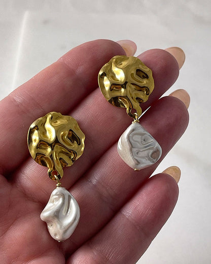 The Pearl Shell Gold Earrings, a pair of gold earrings featuring MOP shell pearls.