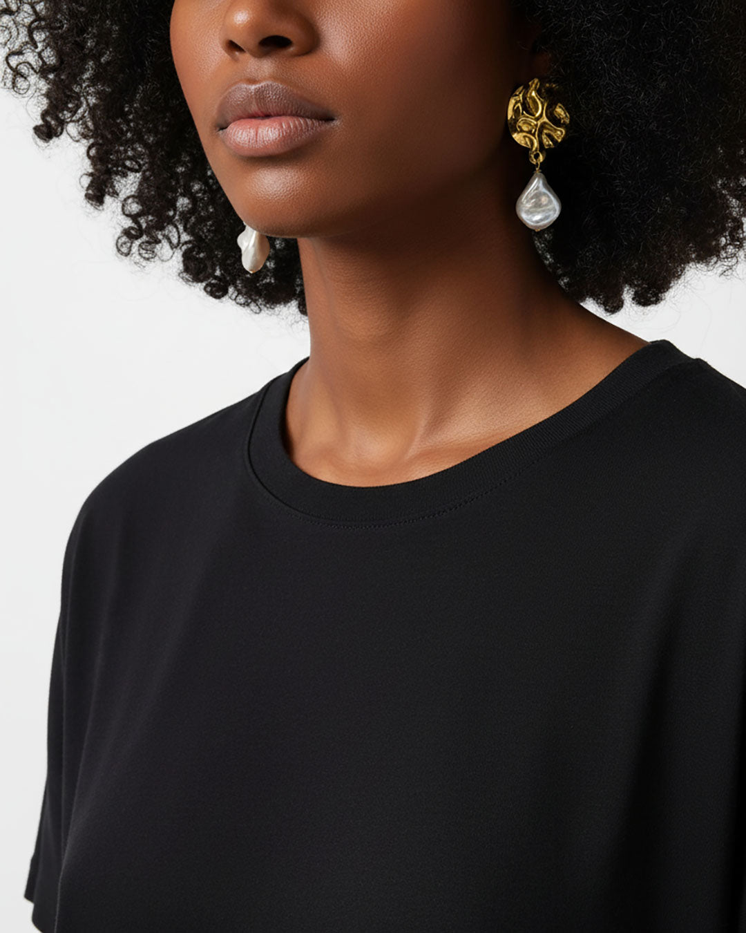 Model wearing a pair of gold earrings featuring MOP shell pearls