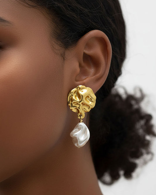Model wearing a pair of gold earrings featuring MOP shell pearls