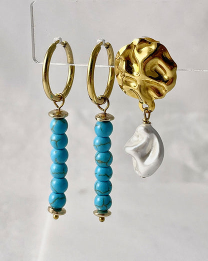 The Turquoise Gem Hoop Earrings, a pair of gold hoop earrings featuring turquoise howlite stones.