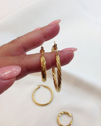 Close up details from 30mm & 45mm twisted gold hoop earrings on fingers