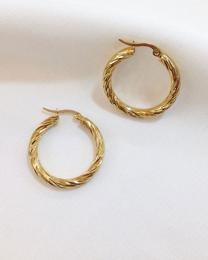 A pair of 30mm twisted gold hoop earrings on a white background.