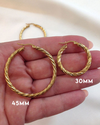 Close up details from 30mm & 45mm twisted gold hoop earrings on fingers