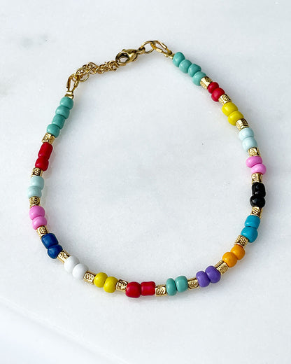 A colorful glass beaded anklet adorned with gold metal beads