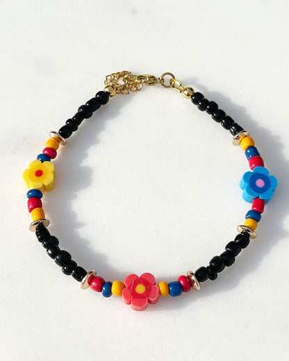 A black glass beaded anklet adorned with colorful daisy flower beads