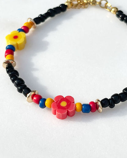A black glass beaded anklet adorned with colorful daisy flower beads