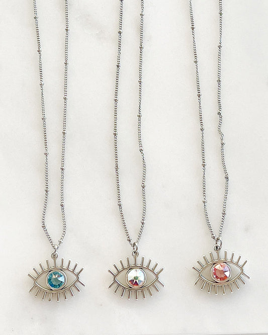 A dainty chain necklace with an evil eye pendant and a Swarovski crystal