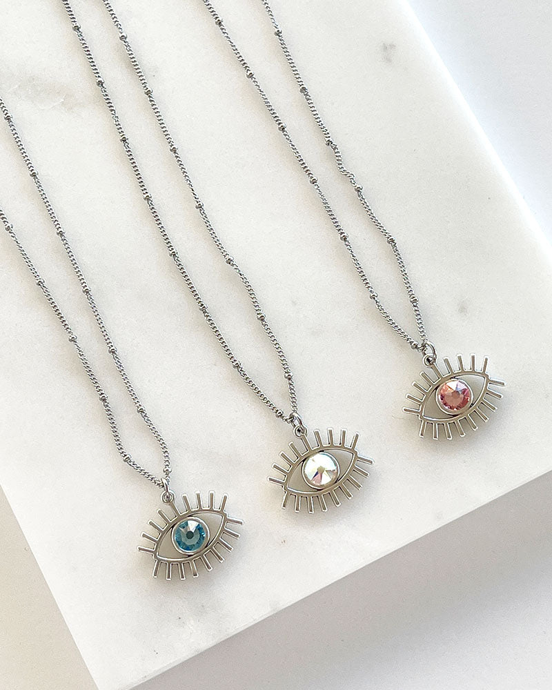 A dainty chain necklace with an evil eye pendant and a Swarovski crystal