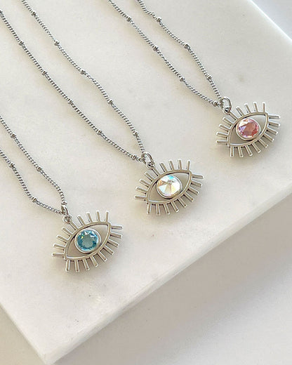 A dainty chain necklace with an evil eye pendant and a Swarovski crystal
