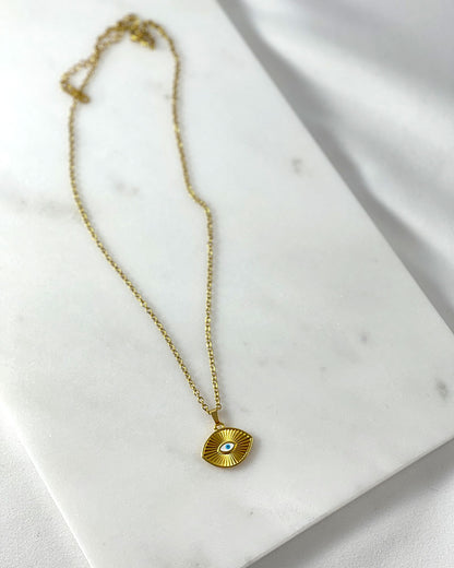 A dainty chain necklace with a small eye pendant. The pendant is gold with a white blue enamel evil eye design.