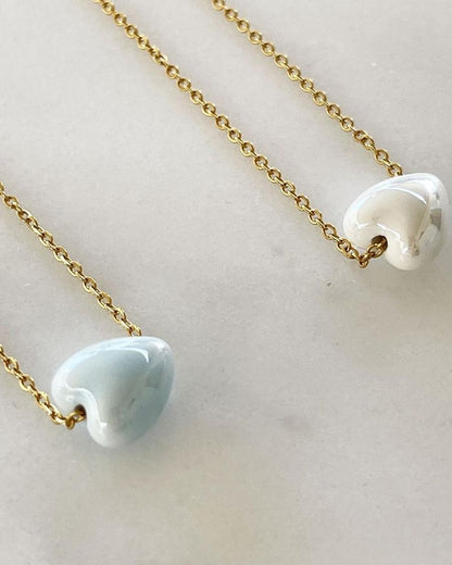 A dainty chain necklace with ceramic heart bead in gold and silver