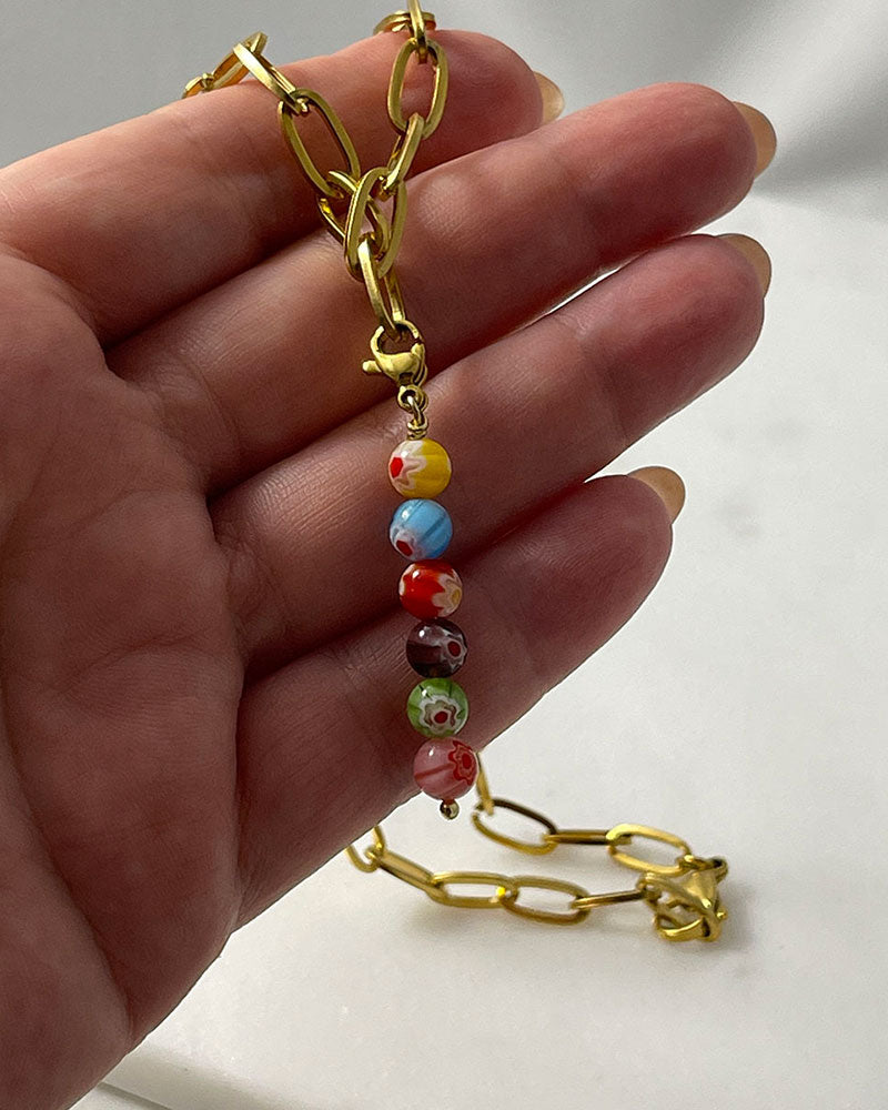 A chunky paperclip chain necklace in gold with a removable murano millefiori beads pendant