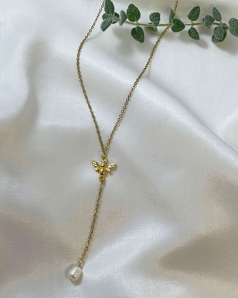 A Bumble Bee Lariat Necklace in gold with a freshwater pearl