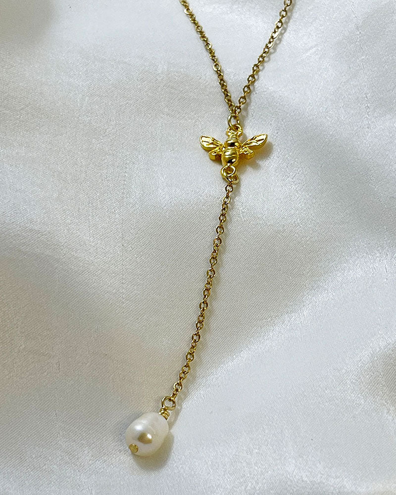 A Bumble Bee Lariat Necklace in gold with a freshwater pearl