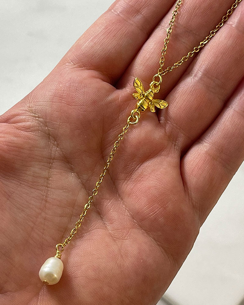 A Bumble Bee Lariat Necklace in gold with a freshwater pearl