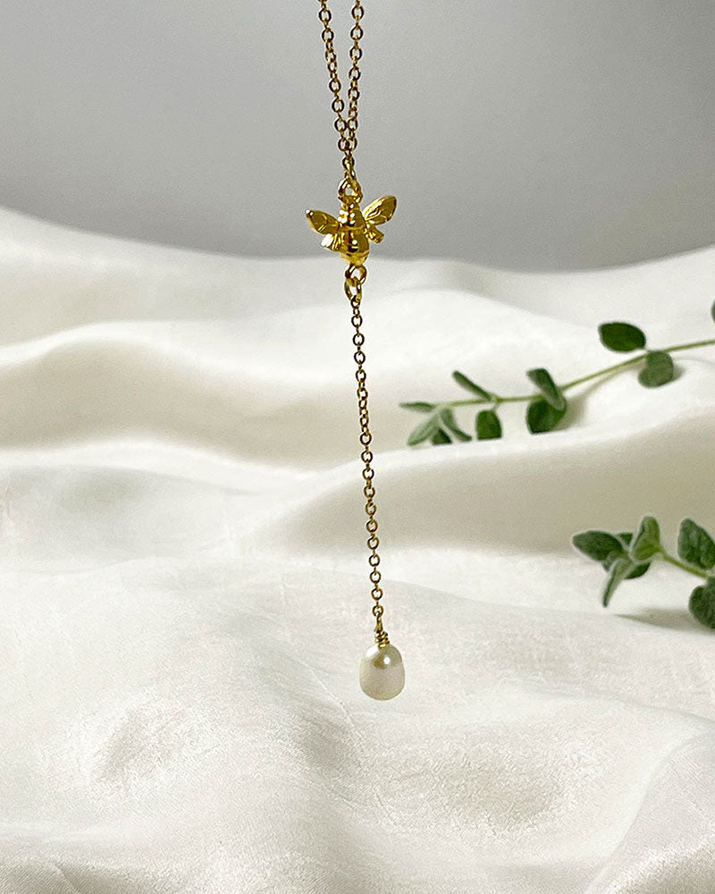 A Bumble Bee Lariat Necklace in gold with a freshwater pearl