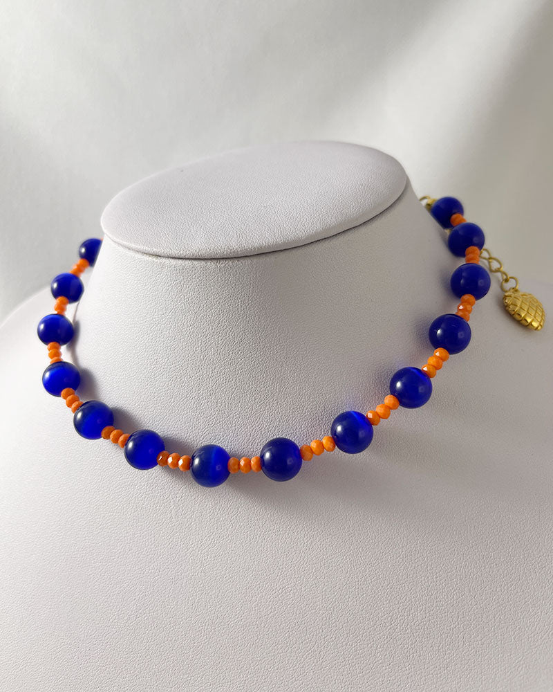 A handmade necklace of blue cat's eye gemstone and orange glass beads