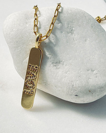 A love engraved tag charm on a dainty paperclip chain in gold