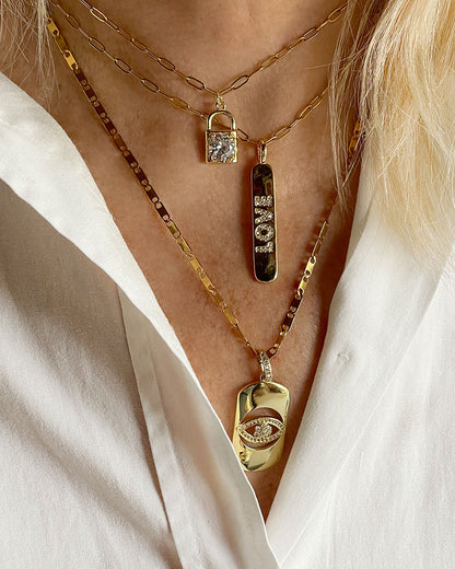 A love engraved tag charm on a dainty paperclip chain in gold