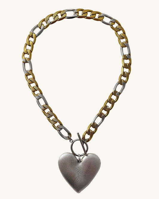 This oversized heart pendant hangs from a statement figaro link chain with a toggle clasp closure!