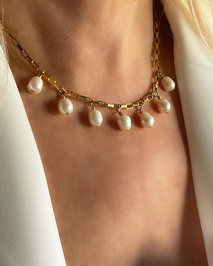 Model wearing a gold chain necklace with multiple white pearl drops