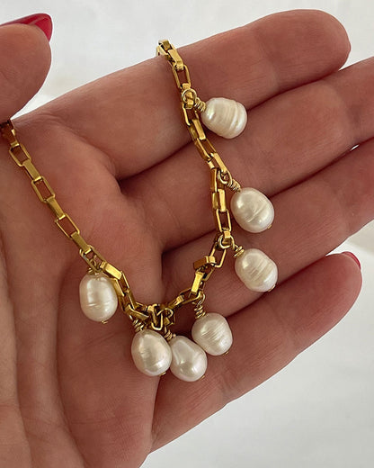 Close-up look of a gold chain necklace with multiple white pearl drops