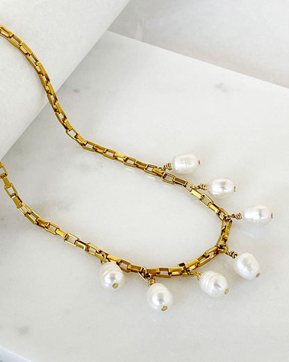 A gold chain necklace with multiple white pearl drops