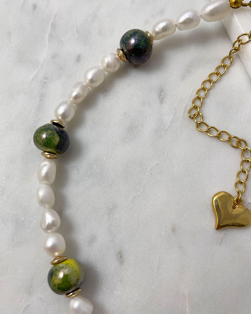 A handmade necklace with freshwater pearls adorned with gold hematite and green ceramic beads