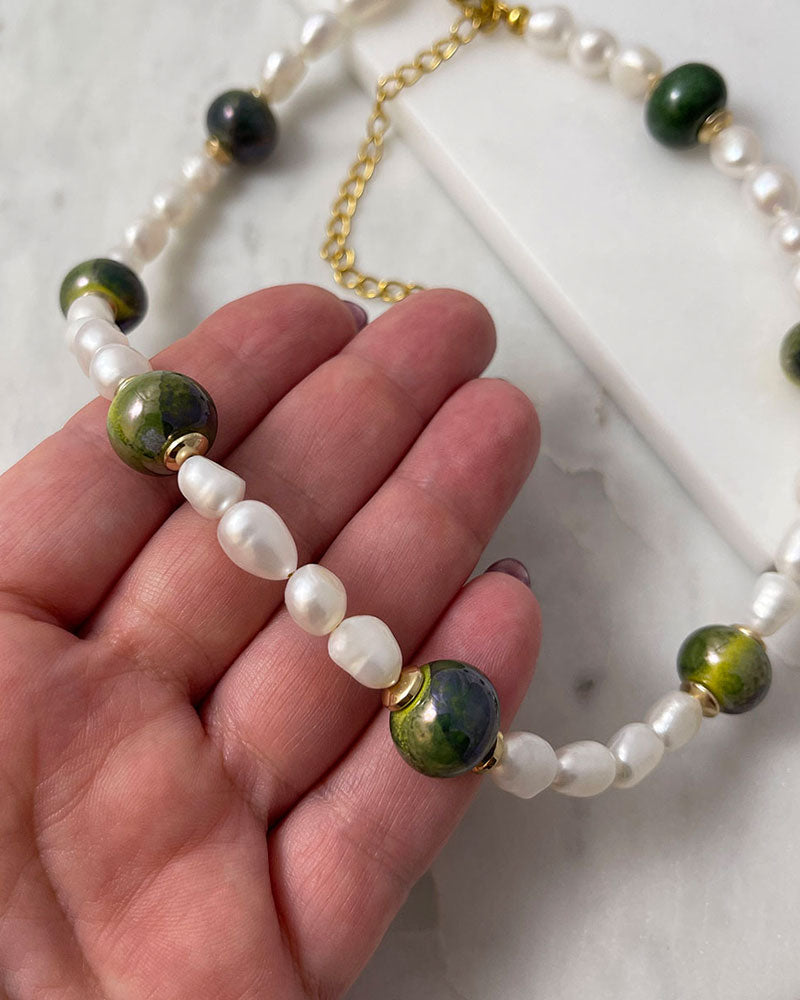 A handmade necklace with freshwater pearls adorned with gold hematite and green ceramic beads