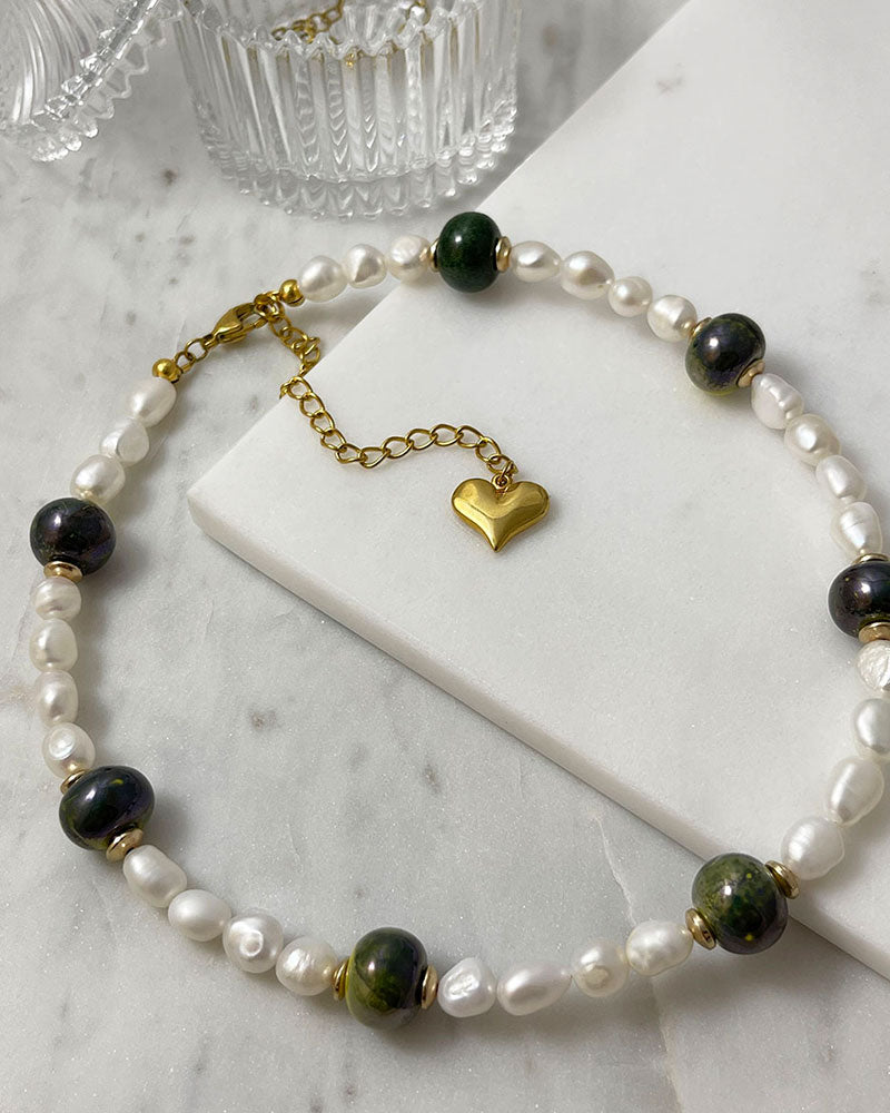 A handmade necklace with freshwater pearls adorned with gold hematite and green ceramic beads