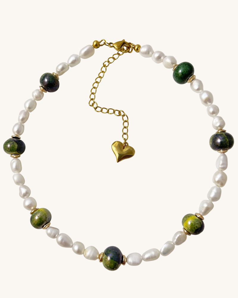 A handmade necklace with freshwater pearls adorned with gold hematite and green ceramic beads