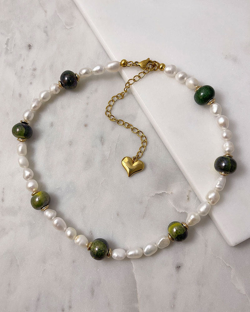 A handmade necklace with freshwater pearls adorned with gold hematite and green ceramic beads