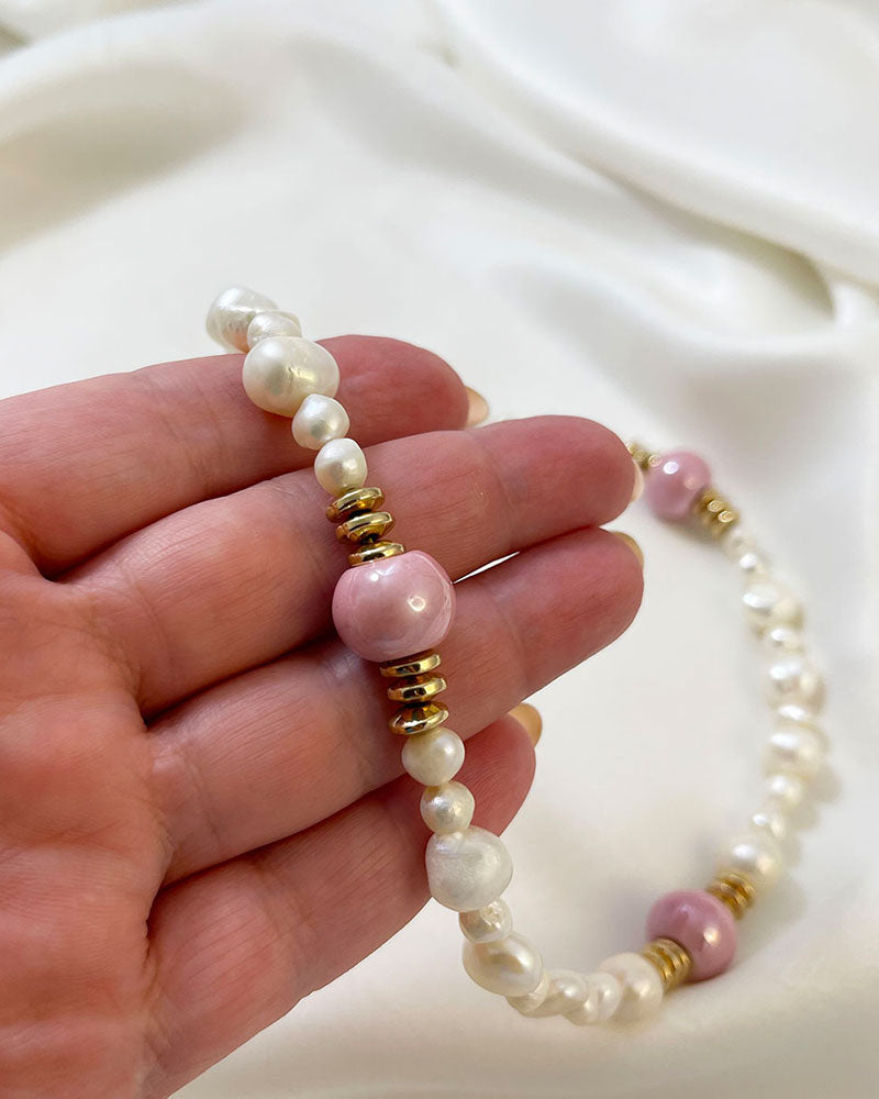 A handmade necklace with freshwater pearls adorned with gold hematite and pink ceramic beads