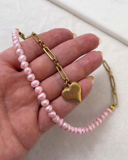 A pink freshwater pearl statement lariat necklace with a gold paperclip chain and a hanging heart pendant
