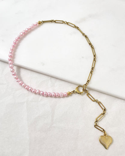 A pink freshwater pearl statement lariat necklace with a gold paperclip chain and a hanging heart pendant