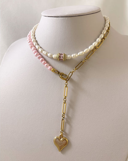 A pink freshwater pearl statement lariat necklace with a gold paperclip chain and a hanging heart pendant