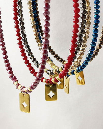 Shiny glass beaded necklaces in different colors with a gold star tag pendant.
