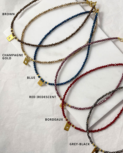 Shiny glass beaded necklaces in different colors with a gold star tag pendant.